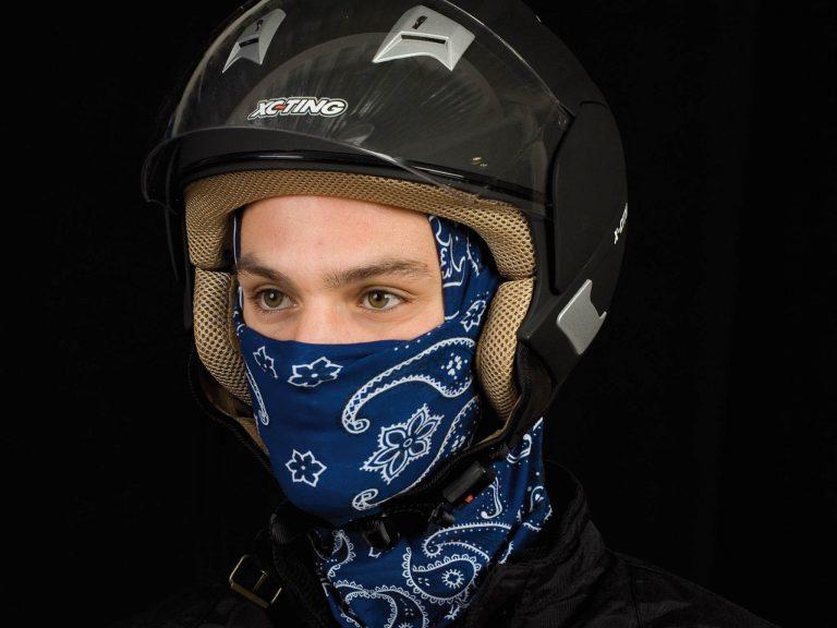 A portrait frontal, full face photo of a man wearing a Original Buff® as helmet liner under his open face motorcycle touring helmet. A studio photoshoot with Buff® ambassador Jordi Viladoms in front of a black background. Jordi is wearing the Original Buff® as helmet liner. The front is pulled up to his nose as face mask. Source: buff.eu Copyright: © Original Buff® S.A. Released for the promotion of the Original Buff® in motorcycling.