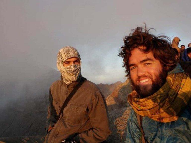 A side landscape selfie of two men smiling in the camera. They are high up in the mountains nearly in the clouds. The right person Rian Cope sports lots of facial hair and a big scarf. The left person is using a Original Buff® to entirely cover his head. Only the eyes are uncovered. Source: Rian Cope www.EatSleepSurf.com.au © Allowed to use on our website