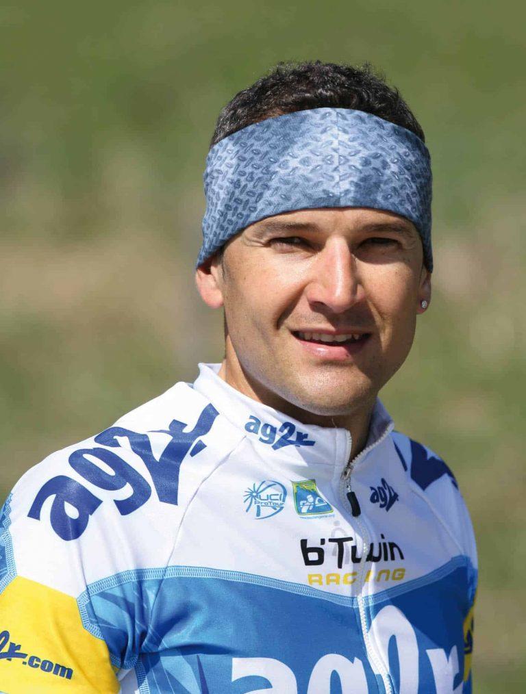 The photo shows a frontal upper body shot of Cyril Dessel before a 2006 Tour De France stage. He is wearing his AG2R team jersey and a Original Buff® as headband. The shun is shining and he looks at ease. Source: buff.eu Copyright: Distributed for the promotion of Original Buff® products