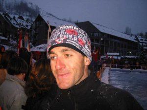 A landscape side shot of a man wearing a Polar Buff® as hat / beanie. It looks like it's apres ski time in a ski resort. There are a lot of country flags displayed so I assume it is an international event. The man looks happy with slightly glassy eyes. He seems to be in his comfort zone.