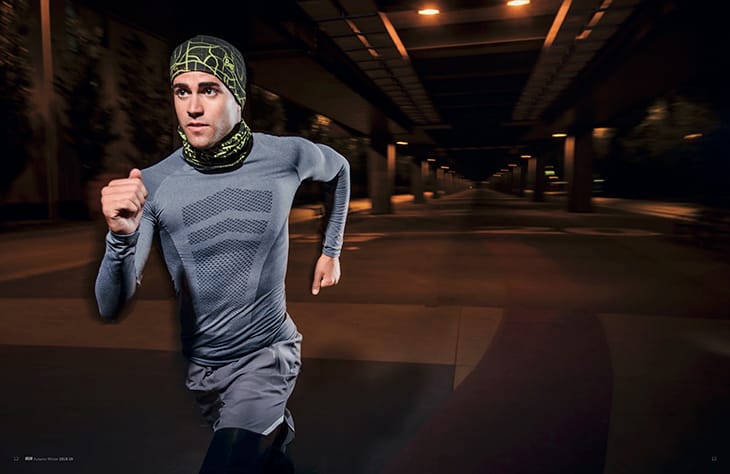 A photo of a young man running at night through a city. The reflective elements of the BUFF® DryFLX are clearly visible. Source: buff.eu